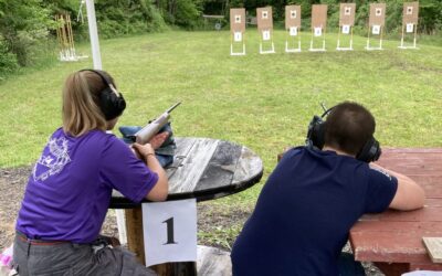A male and female Scout aim their rifles at targets on the shooting range